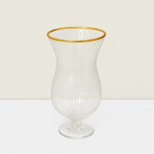 A glass vase with gold rim on a white surface.
